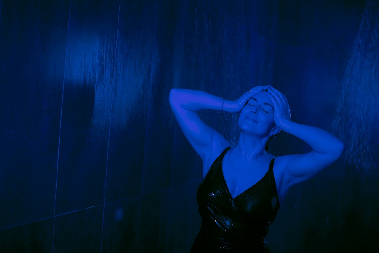 Woman standing under the Rain Walk shower with water flowing over her hair.